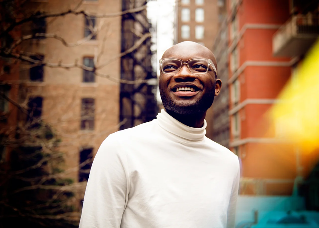 Kofi smiling between two tall buildings