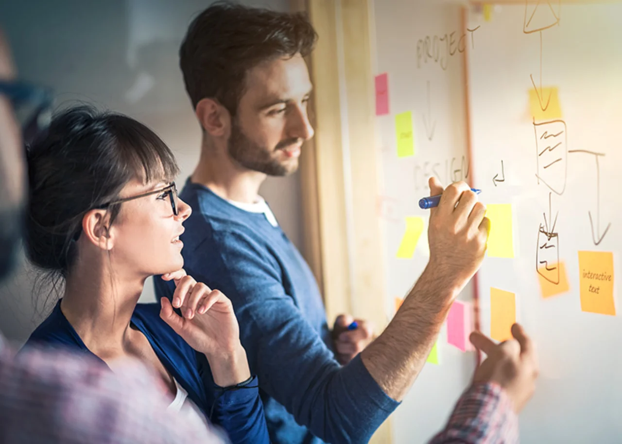 zwei Personen vor einem Whiteboard mit Post-its